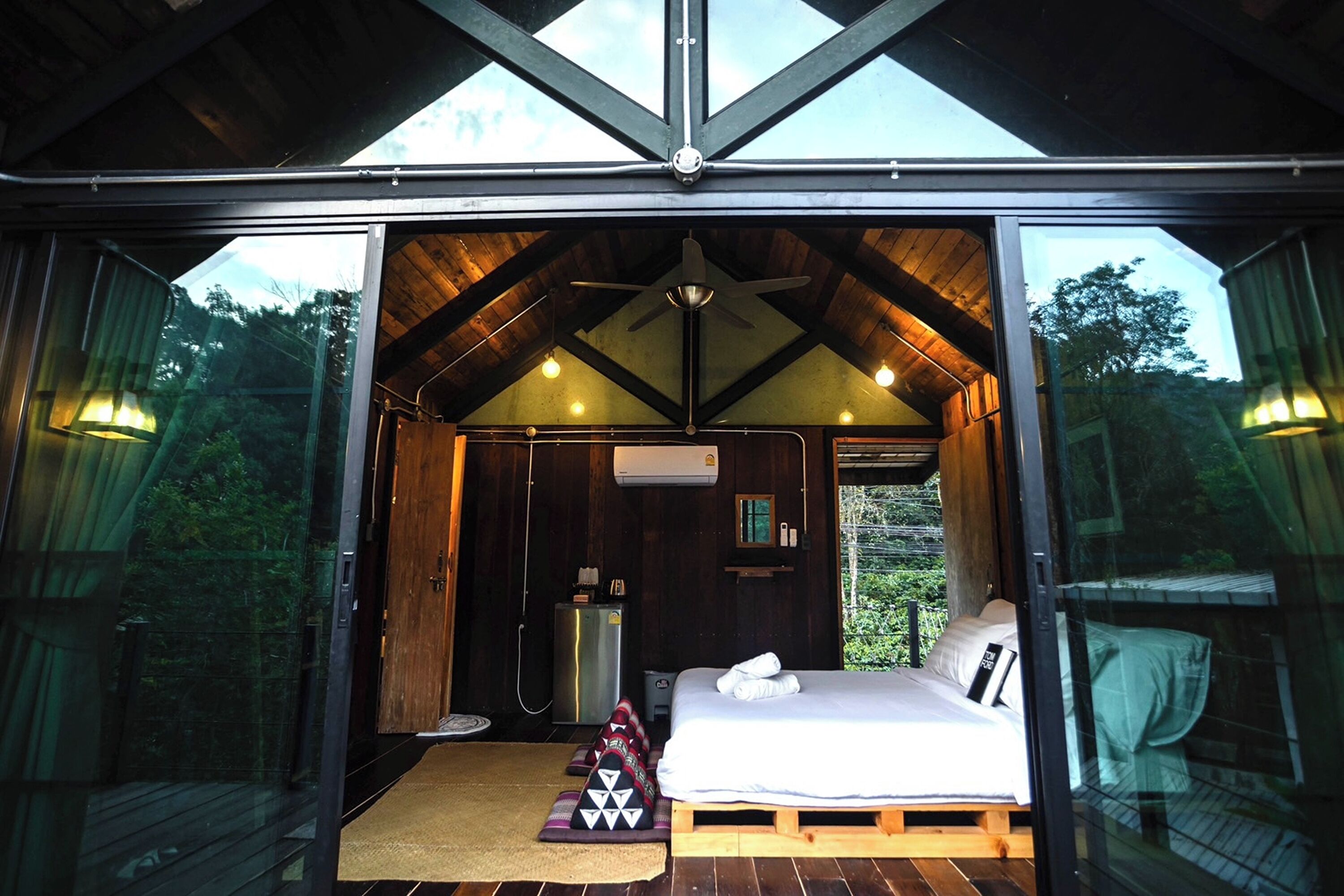 A cozy, well-lit bedroom with a bed, a ceiling fan, and a small bedside table.