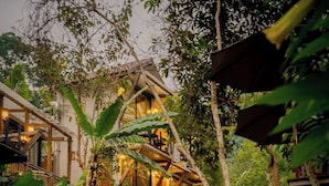 A rustic lodge with a waterfall, surrounded by lush vegetation. - Voraman Hut (Doi Saket)