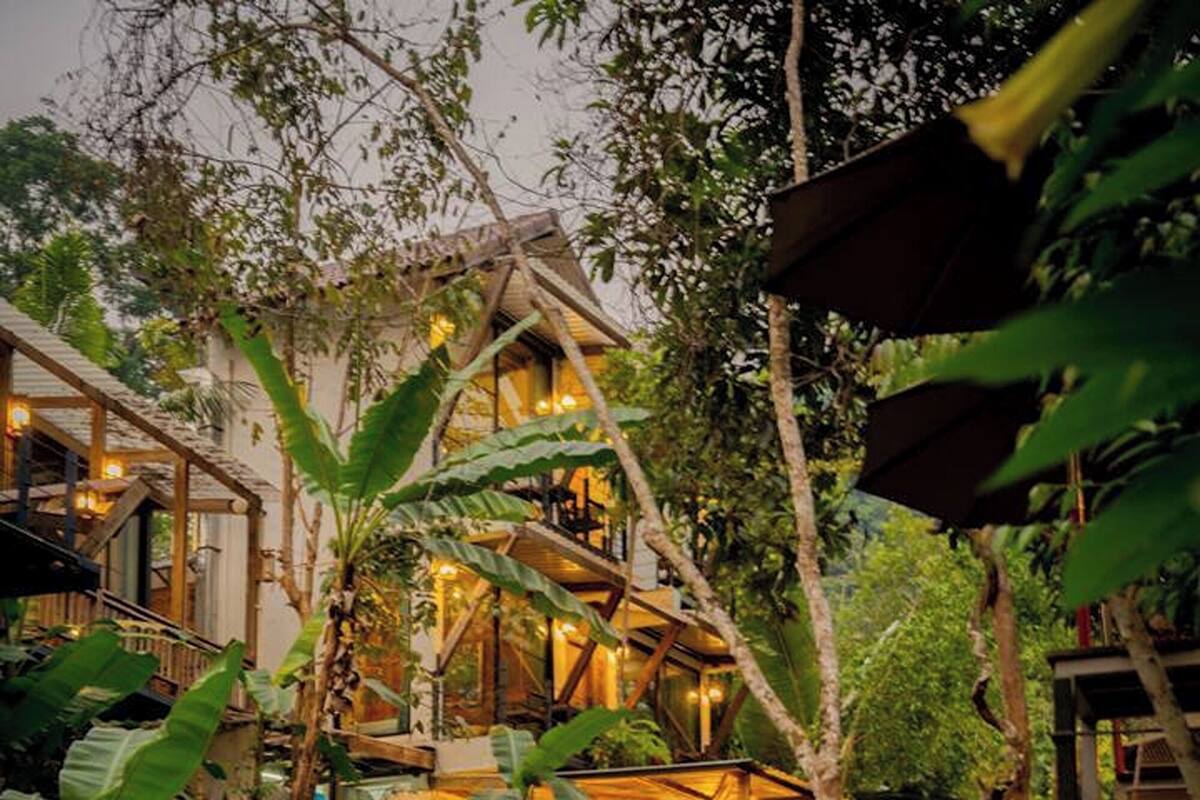 A rustic lodge with a waterfall, surrounded by lush vegetation.