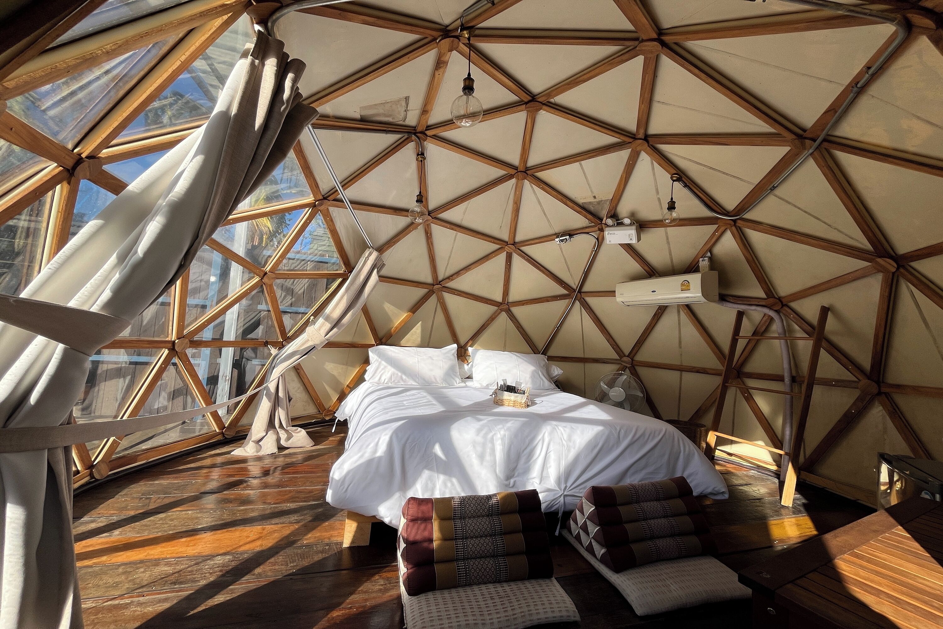 Una habitación abovedada con una cama, almohadas y suelo de madera.