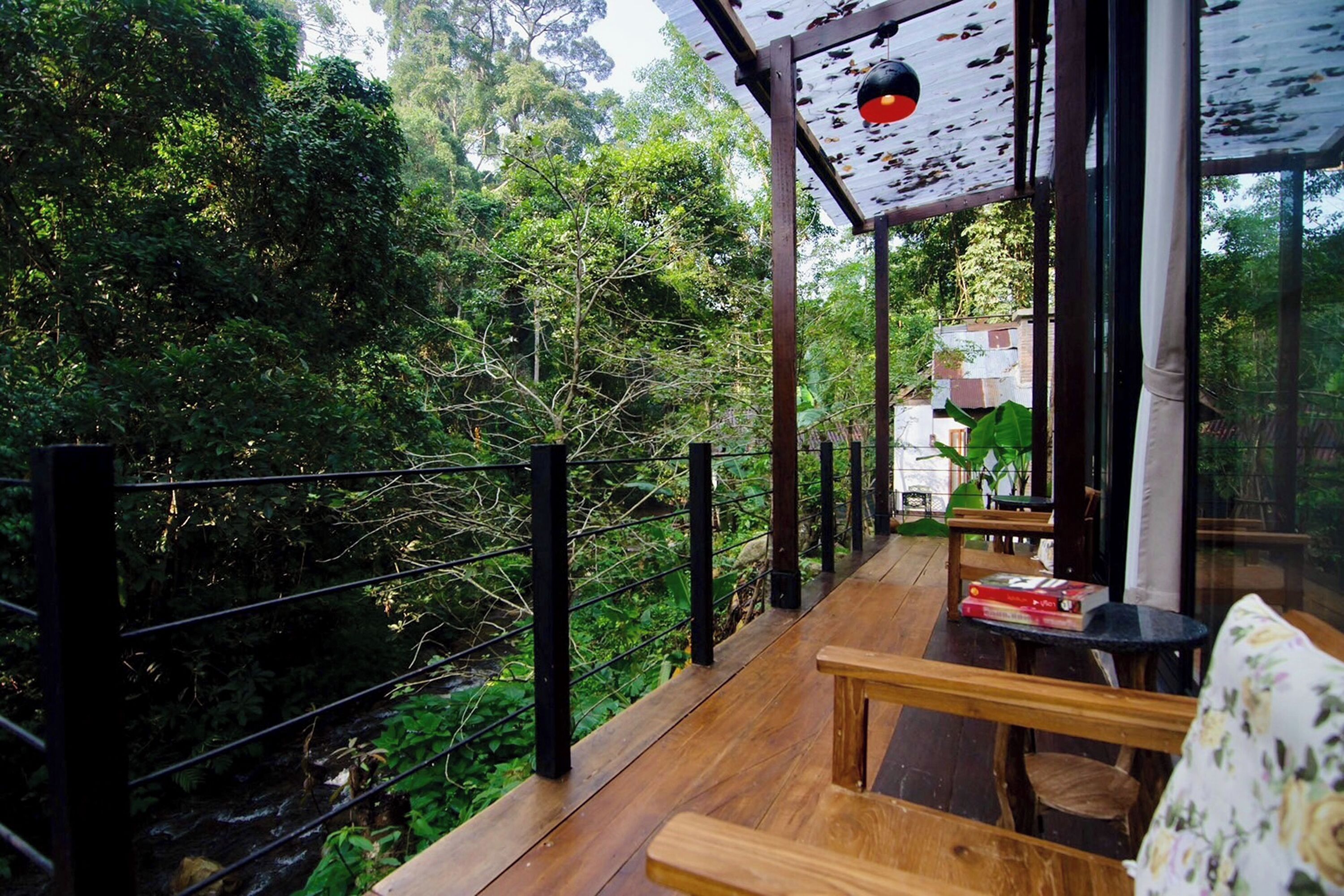 Una terraza de madera con barandilla negra que da a un bosque frondoso.