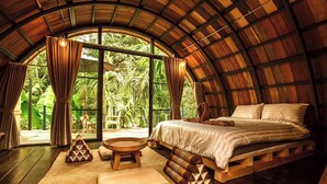 A bedroom with a wooden ceiling, a bed, a window, and a view of greenery outside. - Voraman Hut (Doi Saket)