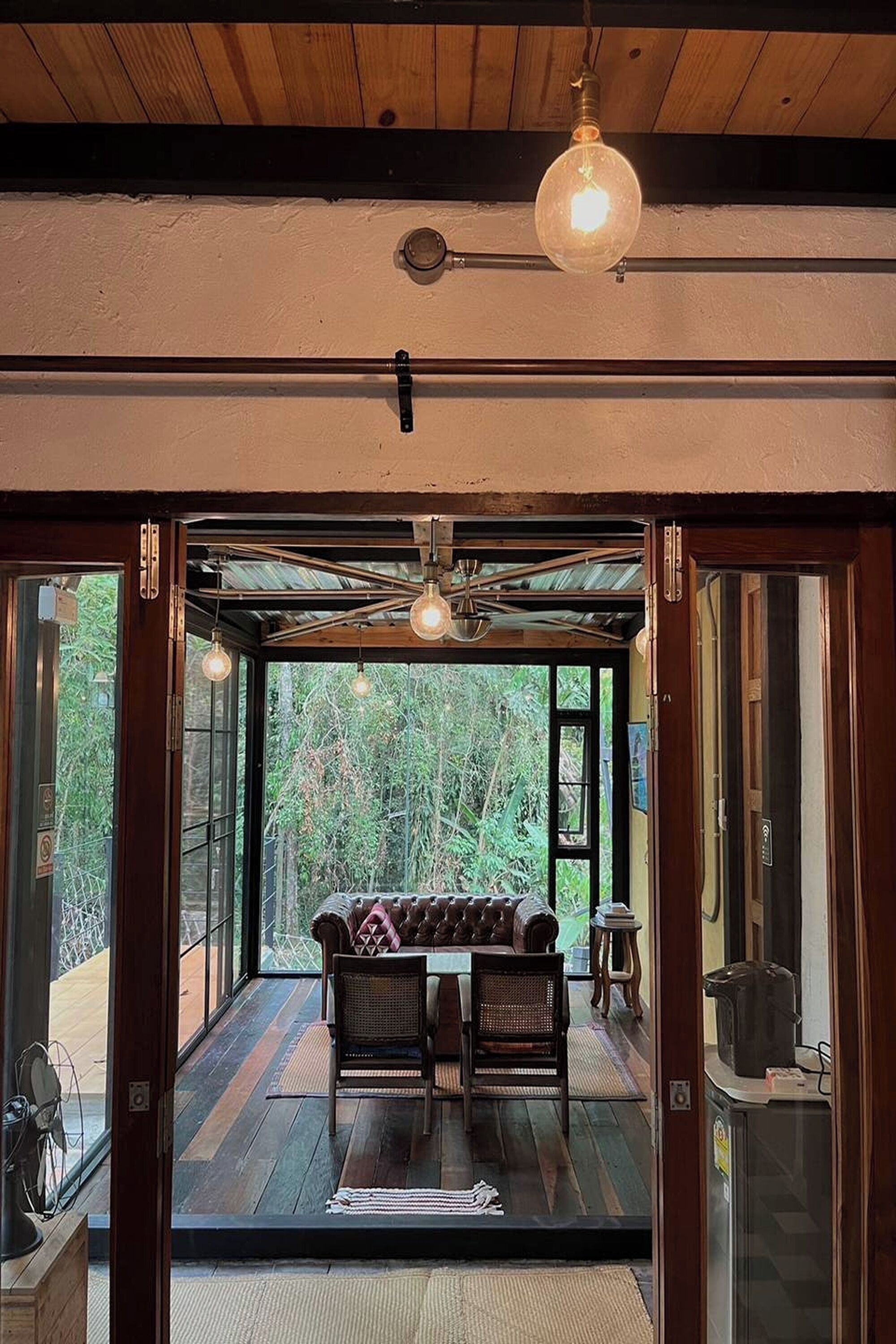 Una habitación acogedora con techo de madera, una mesa de comedor con sillas y una lámpara colgante.