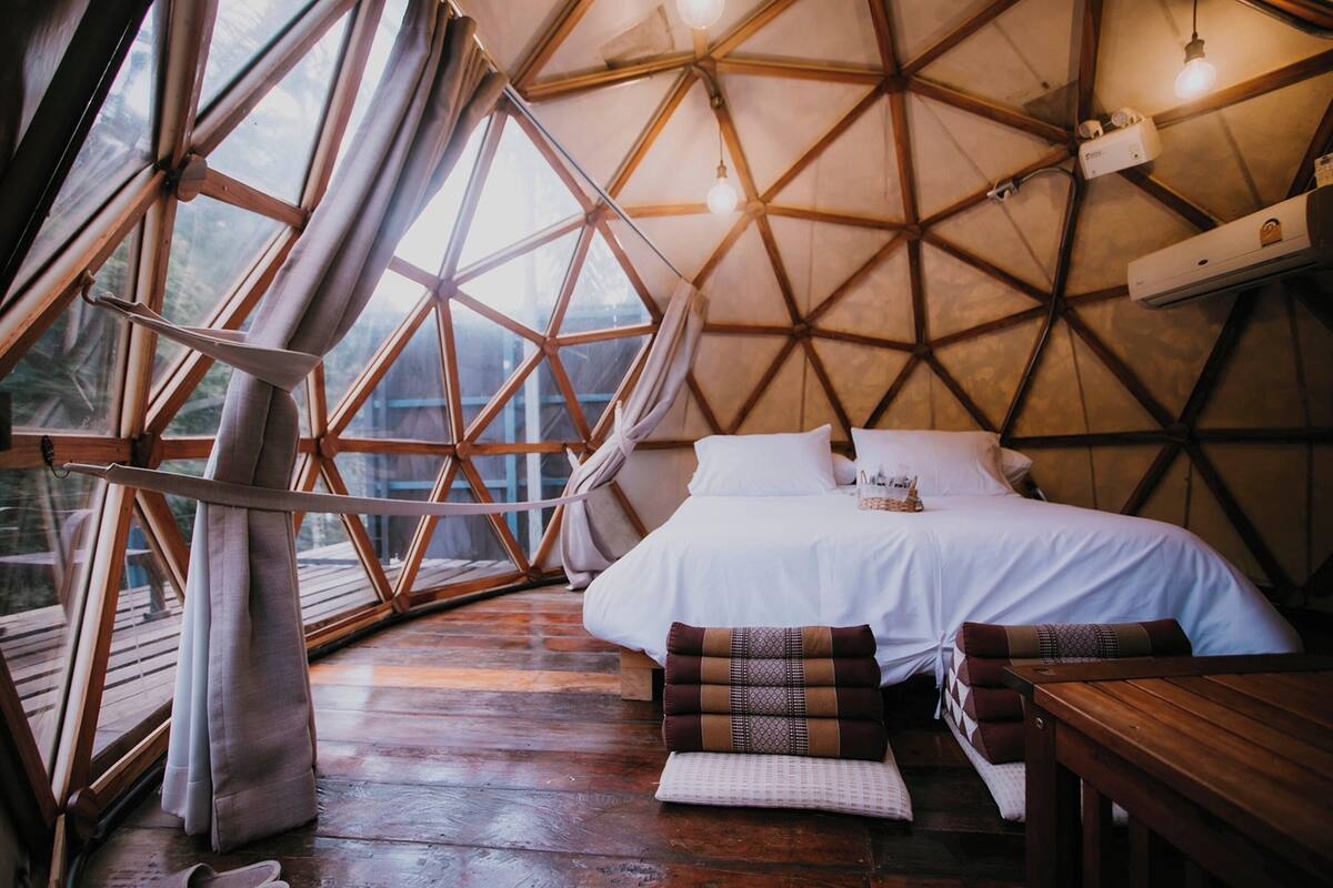 A cozy room with a bed, pillows, and a wooden table.