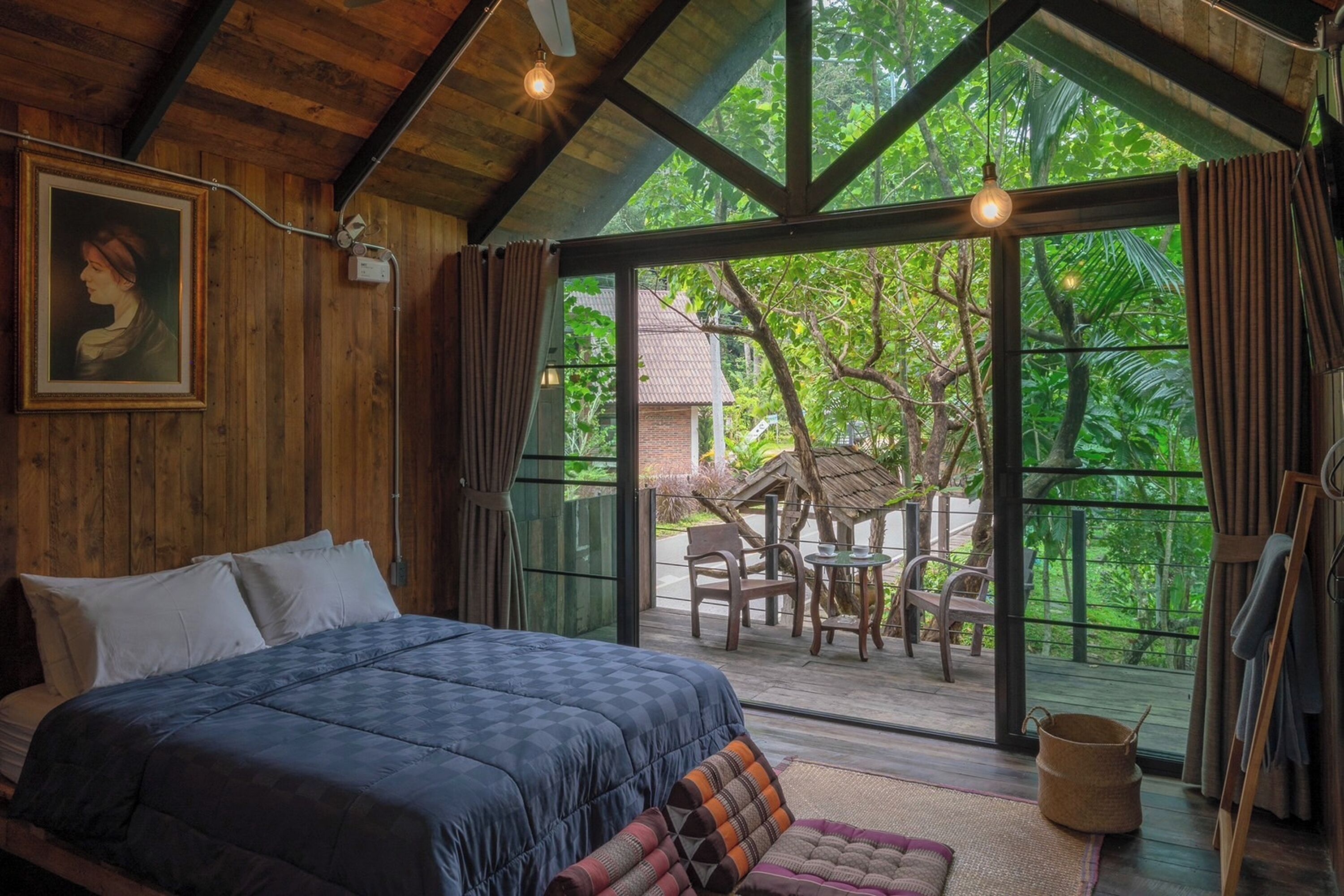 Un dormitorio con una cama grande, paredes de madera y vistas a un jardín tropical.