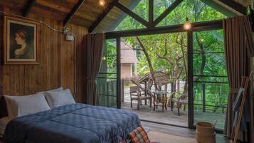 Un dormitorio con una cama grande, paredes de madera y vistas a un jardín tropical.
