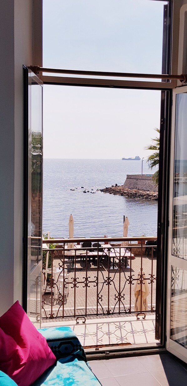 Un balcon avec vue sur la mer, une table avec des chaises et une rambarde.