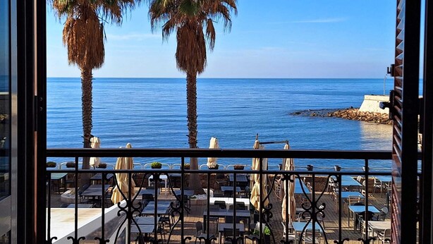 A balcony with a view of the sea, palm trees, and outdoor seating. - Mowita seaside flat with stunning view on the sea (Civitavecchia)