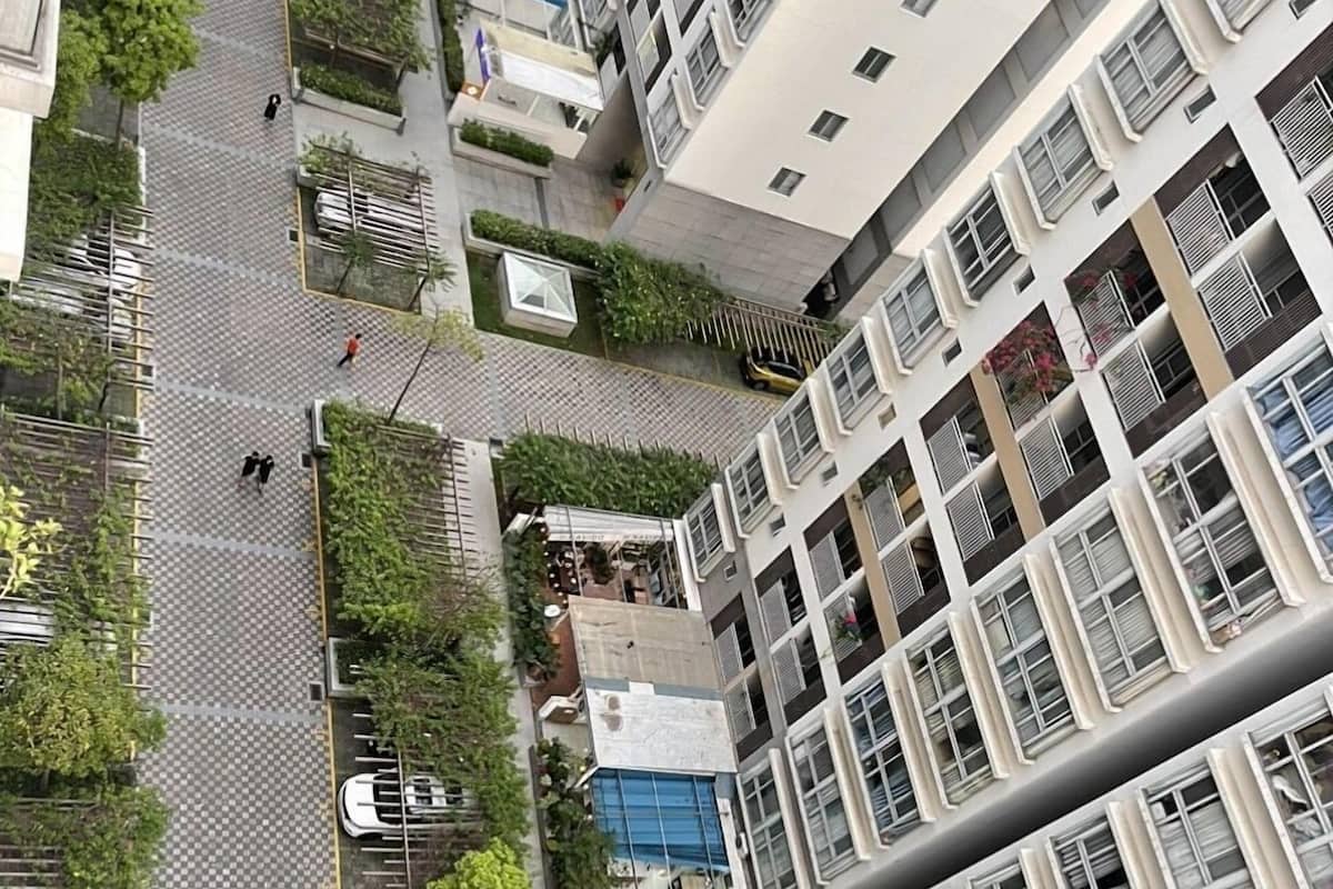 A high-rise building with multiple balconies, a parking area, and a small garden space.