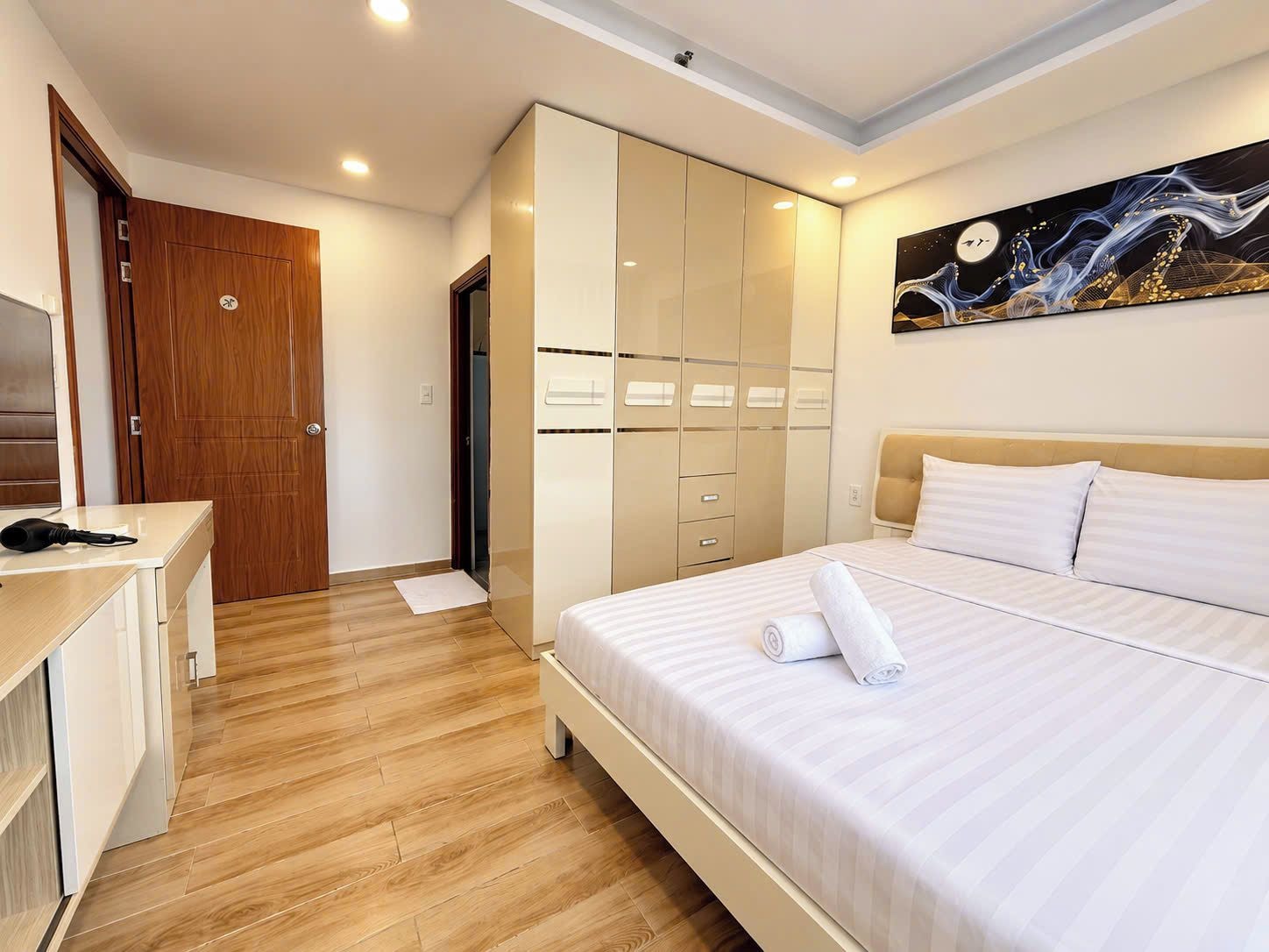 Une chambre d’hôtel avec un lit, un bureau, une armoire et un tableau au mur.