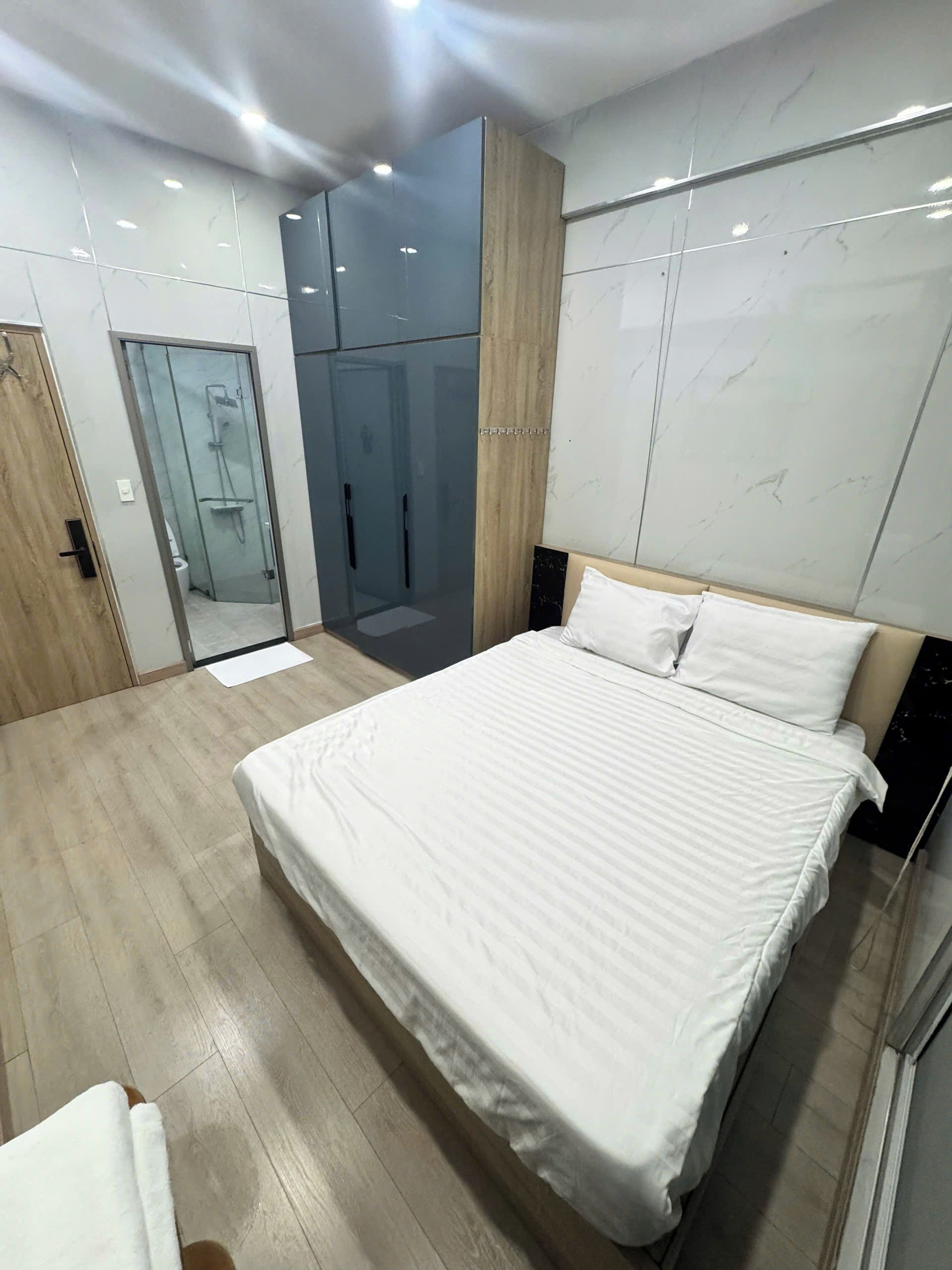 A bedroom with a large bed, a wardrobe, and a bathroom visible through a glass door.