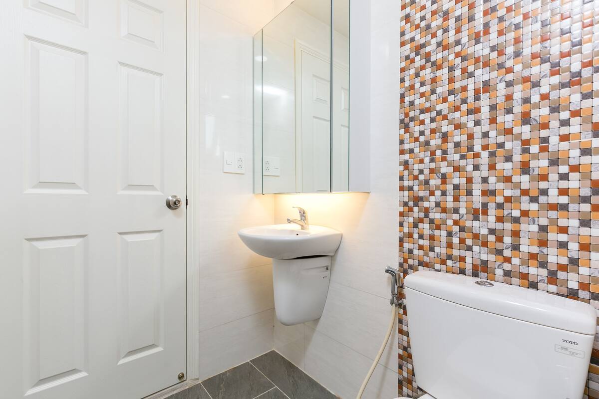 A bathroom with a white door, a sink, and a toilet.