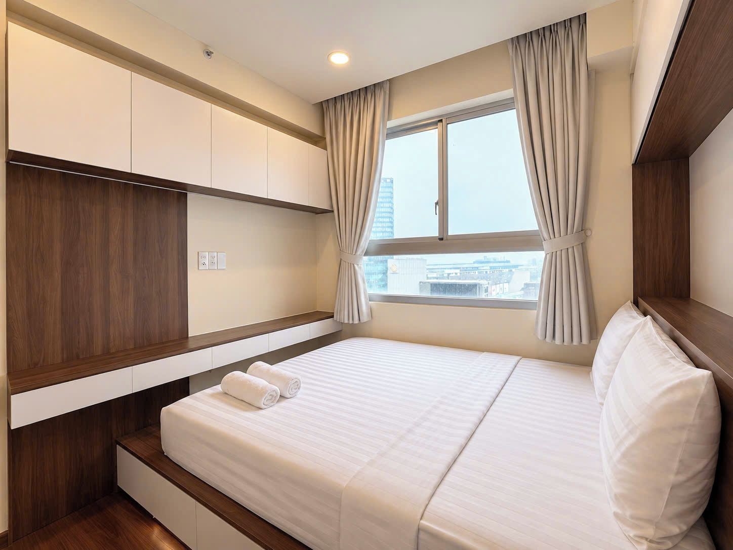 A hotel room with a bed, built-in wardrobe, and a window with curtains.
