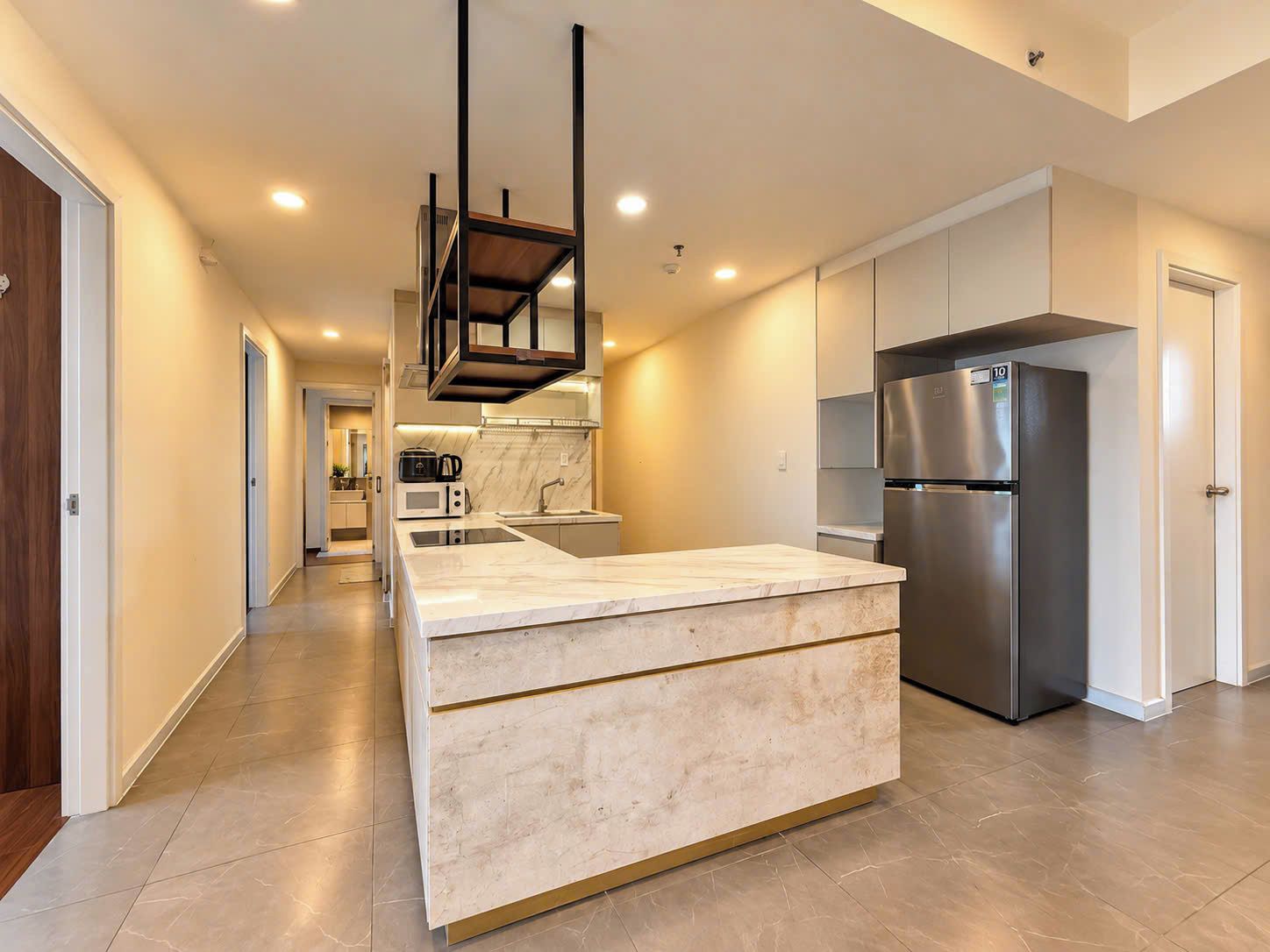 A modern kitchen with a central island, stainless steel appliances, and a marble backsplash.
