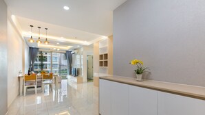 A modern hotel lobby with a reception desk, a dining area with a table and chairs, and a large window with curtains. - Scenic Valley - Vina We Stay Apartment (Ho Chi Minh City)