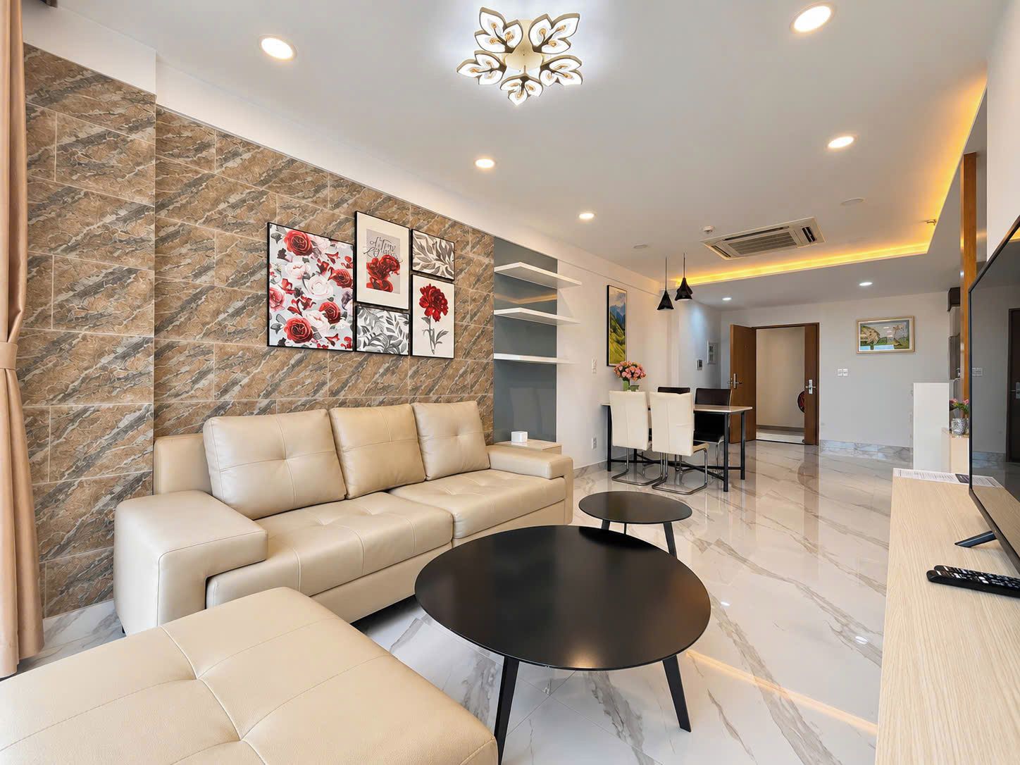 A modern living room with a sofa, a coffee table, and a dining area with chairs and a table.