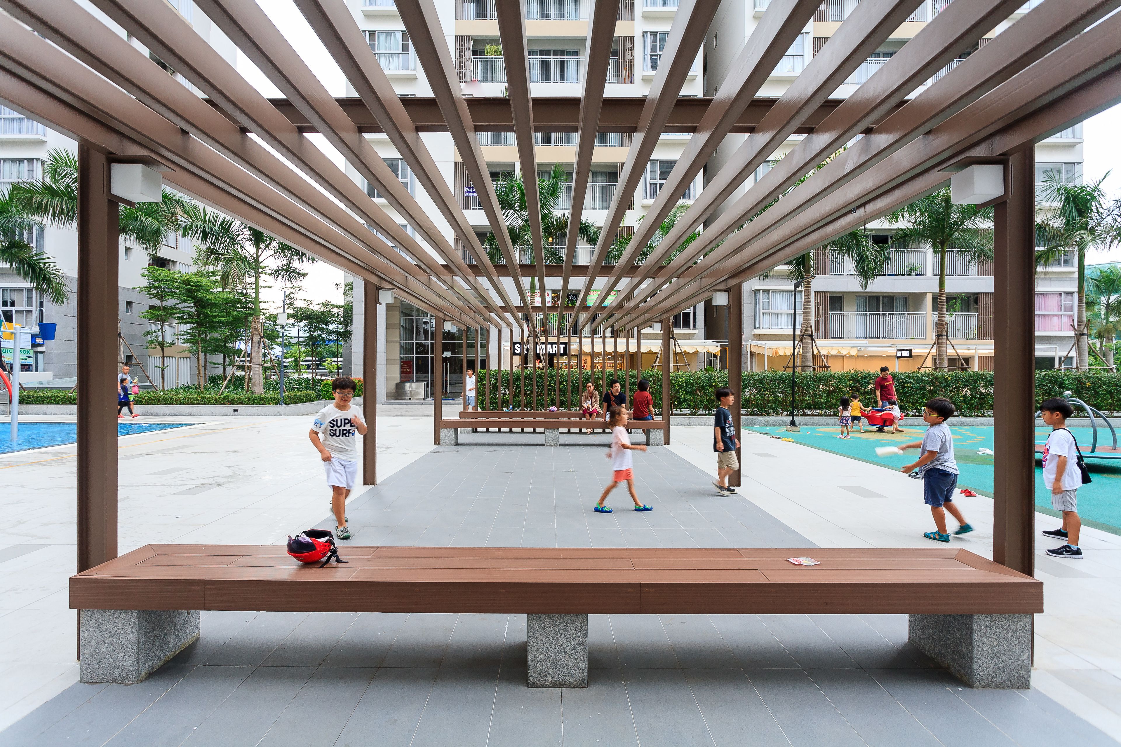 An outdoor seating area with a wooden bench and a metal roof structure.