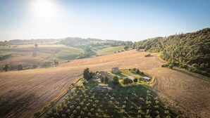 An aerial view of a rural landscape with rolling hills, fields, and a small cluster of buildings. - Apartment I Reucci Trilo2 (Pomarance)