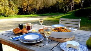 A table set with food and drinks, including a bowl of rice, bread, and a glass of wine, in a garden setting. - A haven of peace in the village of Montrésor (Châteaux de la Loire) (Chemillé-Sur-Indrois)