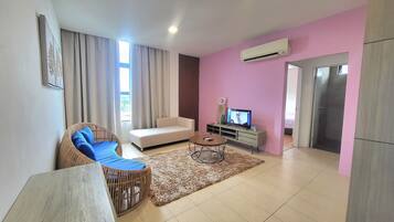Una sala moderna con un sofá, un sillón de mimbre, una mesa de centro y una televisión.