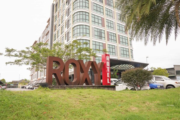 A hotel sign with the name "ROXY HOTEL" in front of a modern building with multiple floors and large windows. - Roxy Hotel 3rd Mile (Kuching)