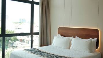 Una habitación de hotel moderna con una cama grande, vistas de la ciudad y una ventana con cortinas.