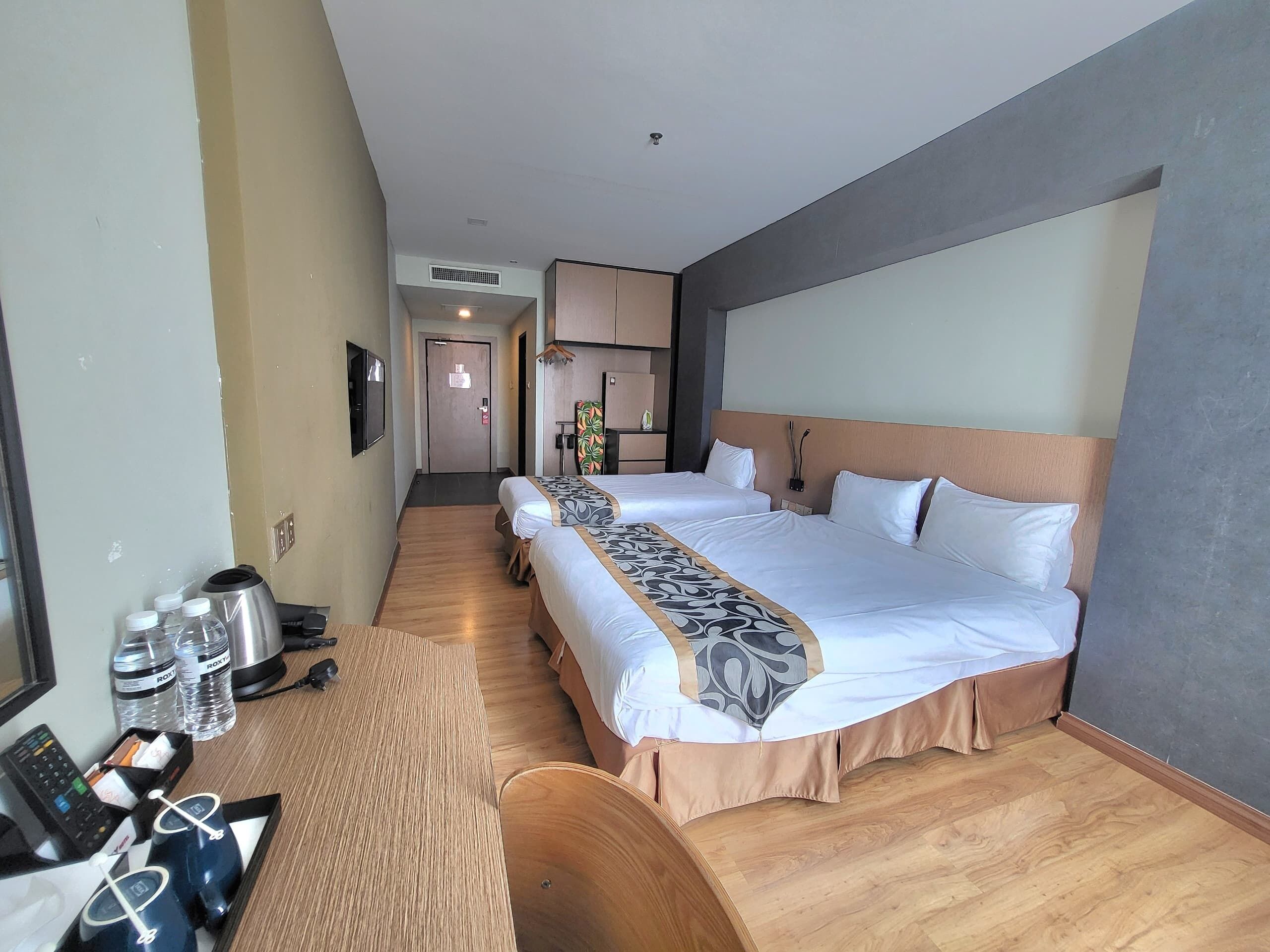 Une chambre d’hôtel avec deux lits, un bureau doté d’un téléphone et d’une machine à café, ainsi qu’un petit coin salon.