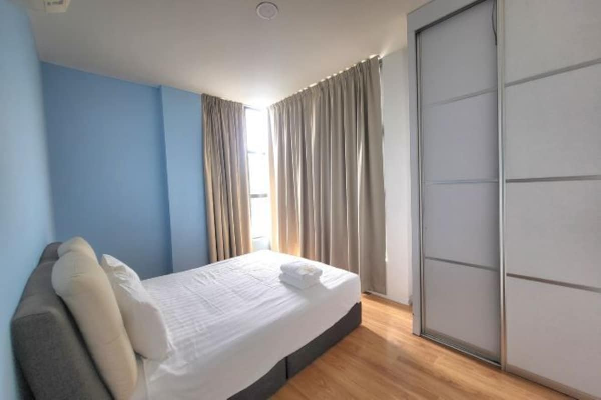 Una habitación de hotel con cama, armario y ventana con cortinas.