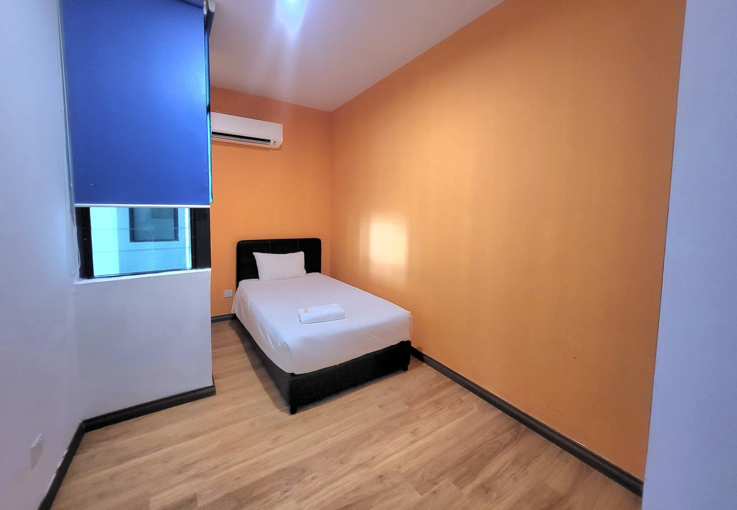 Un dormitorio pequeño y ordenado con una cama individual, un ventanal y un equipo de aire acondicionado.