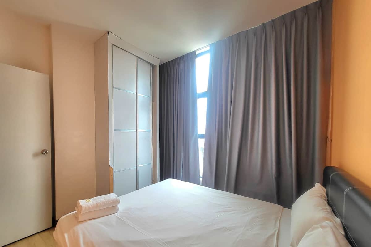 A hotel room with a bed, a wardrobe, and a window with curtains.