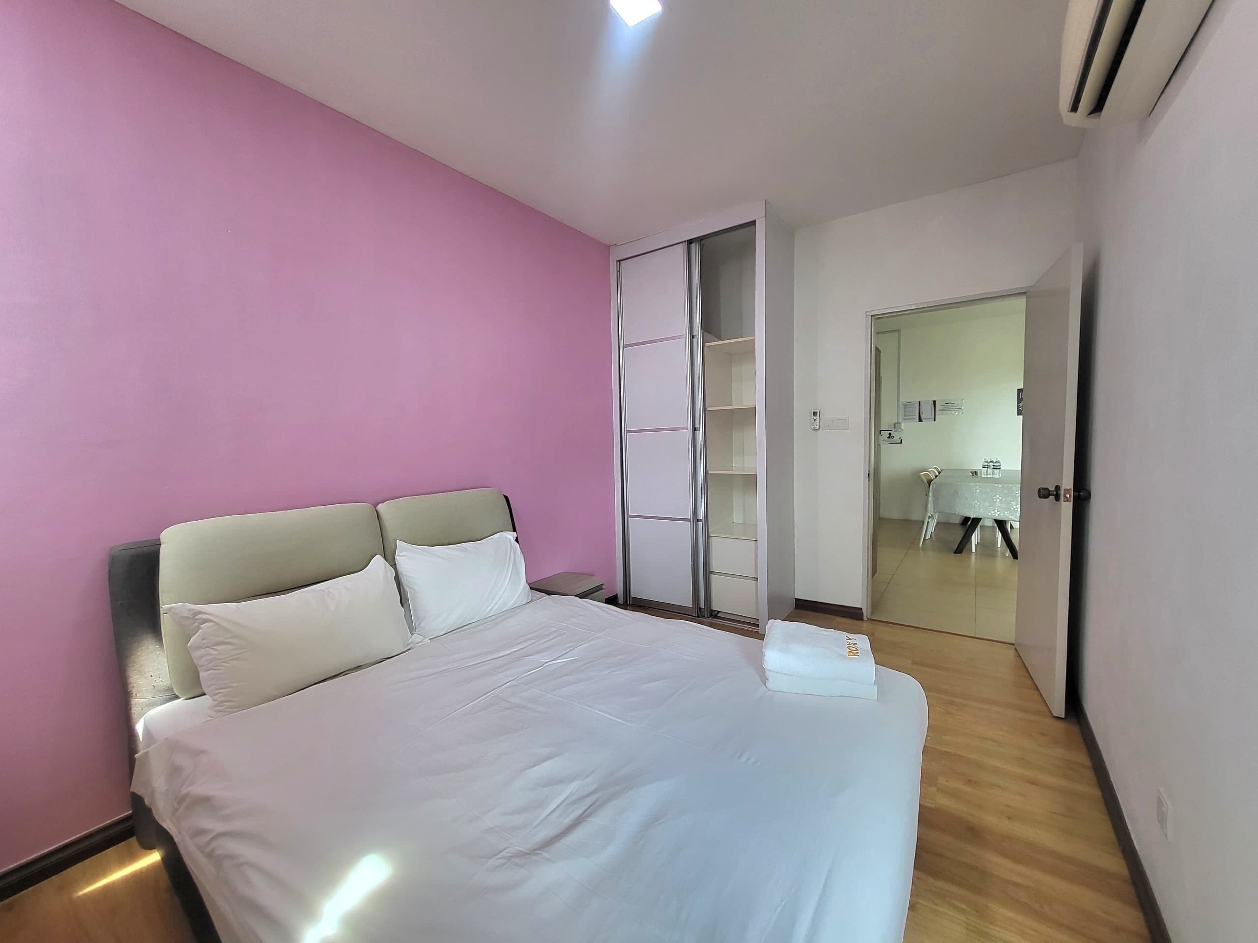 A hotel room with a bed, a wardrobe, and a bathroom visible through an open door.