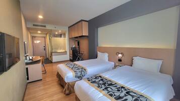 Une chambre d’hôtel avec deux lits, un bureau, un miroir et un espace douche.