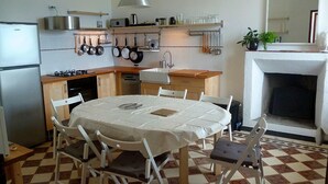 A compact kitchen with a dining table, chairs, a refrigerator, a stove, and a fireplace.