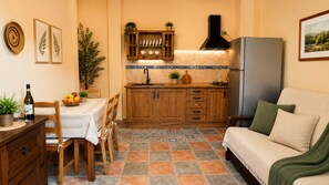 A compact kitchen with wooden cabinets, a built-in oven, and a dining area with a table set for two. - San bartolome de tirajana casa rural casa rural private pool wi-fi Gratis (Santa Lucia De Tirajana)
