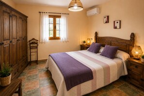 A bedroom with a bed, wooden wardrobe, window with curtains, bedside lamps, and wall-mounted air conditioning unit. - San bartolome de tirajana casa rural casa rural private pool wi-fi Gratis (Santa Lucia De Tirajana)