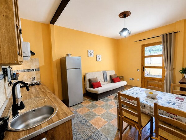 A compact kitchen with a sink, a refrigerator, a dining table with chairs, a sofa, and a window with curtains. - San bartolome de tirajana casa rural casa rural private pool wi-fi Gratis (Santa Lucia De Tirajana)