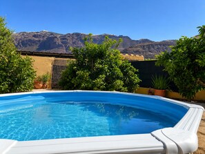 A swimming pool with clear blue water, surrounded by greenery and a mountain backdrop. - San bartolome de tirajana casa rural casa rural private pool wi-fi Gratis (Santa Lucia De Tirajana)