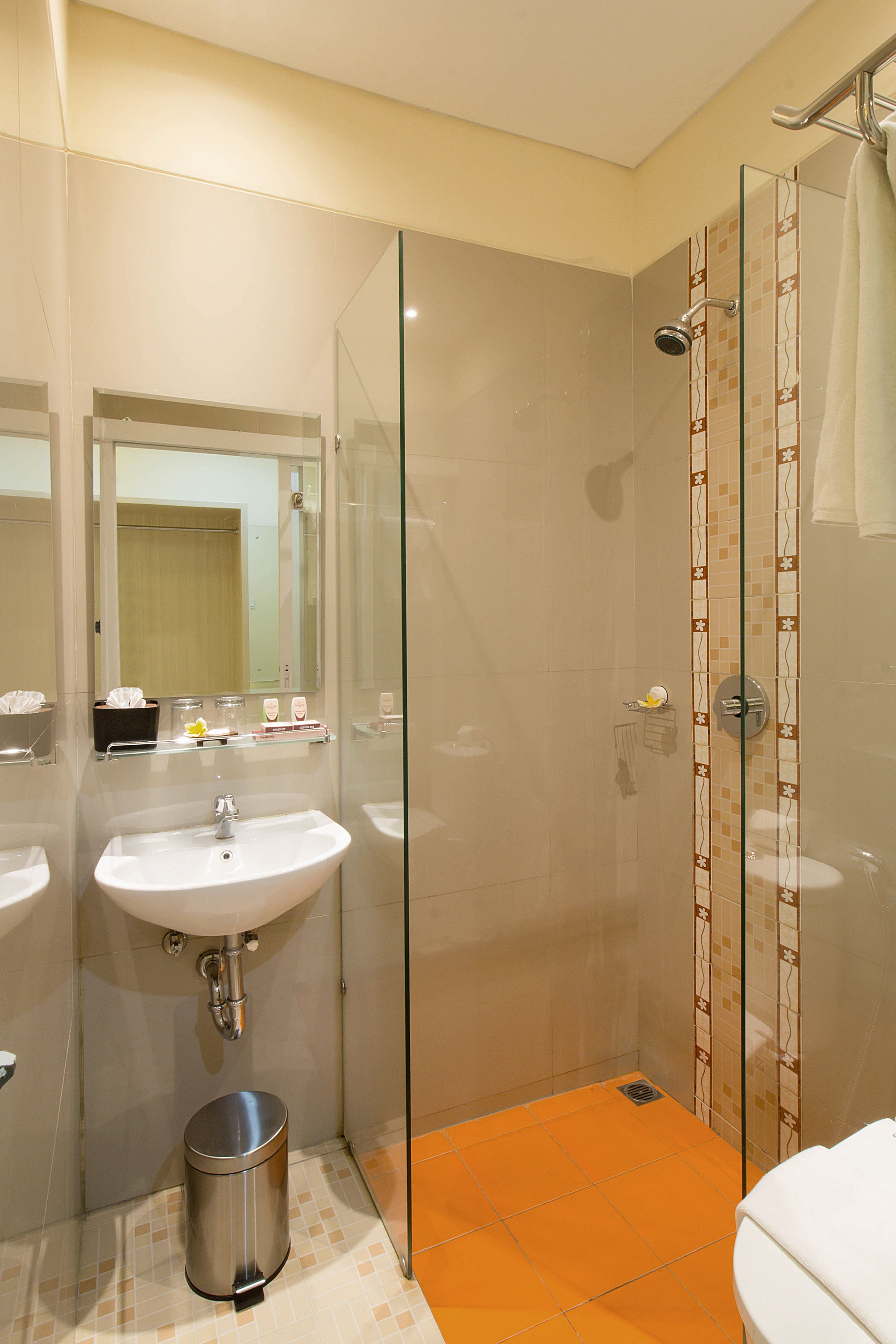 A bathroom with a glass-enclosed shower, a sink, and a toilet.