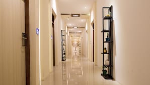A hotel corridor with a polished floor, a reception desk, and a wall-mounted plant shelf. - The Xotic Jimbaran Bali (Jimbaran)