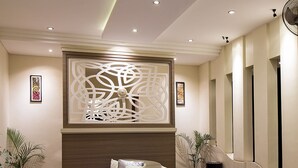 A modern reception area with a curved seating area, a decorative wall panel, and a reception desk. - The Xotic Jimbaran Bali (Jimbaran)