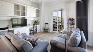 Un salon moderne doté d’un téléviseur à écran plat, de canapés gris, d’un coin repas et d’un balcon offrant une vue agréable.