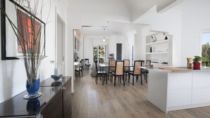 Une cuisine moderne dotée d’un îlot central, d’un coin repas avec des chaises et d’un couloir menant à une autre pièce.