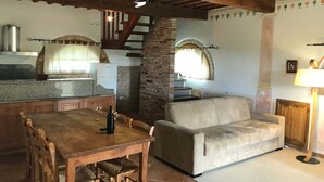 Ein rustikales Interieur mit einem Holzesstisch, einer Couch, einer Steinwand und einer Treppe.