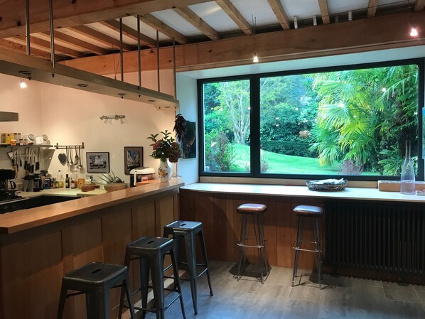 A modern kitchen with a large window, wooden beams, and bar stools. - Mansion - Aste Béon (Aste Béon)