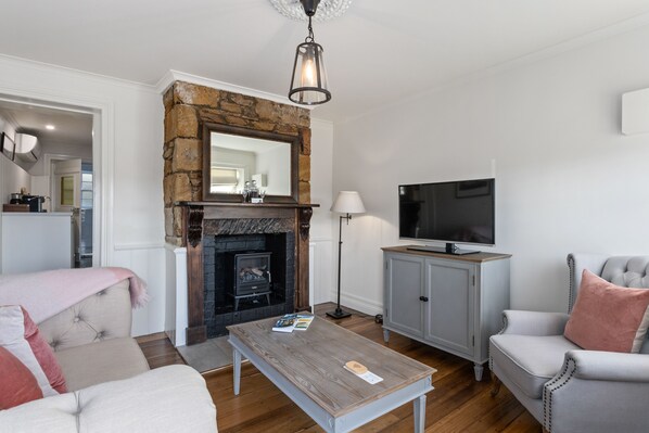A living room with a stone fireplace, a television, a grey armchair, and a coffee table.