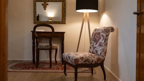 Ein Zimmer mit Holzstuhl, Schreibtisch und Stehlampe.