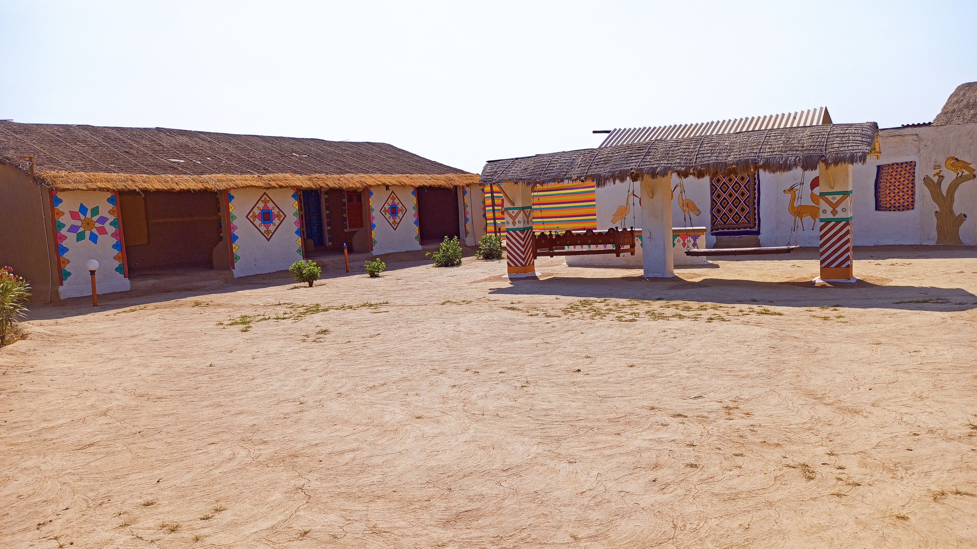 A courtyard with traditional buildings, a swing set, and decorative wall art.