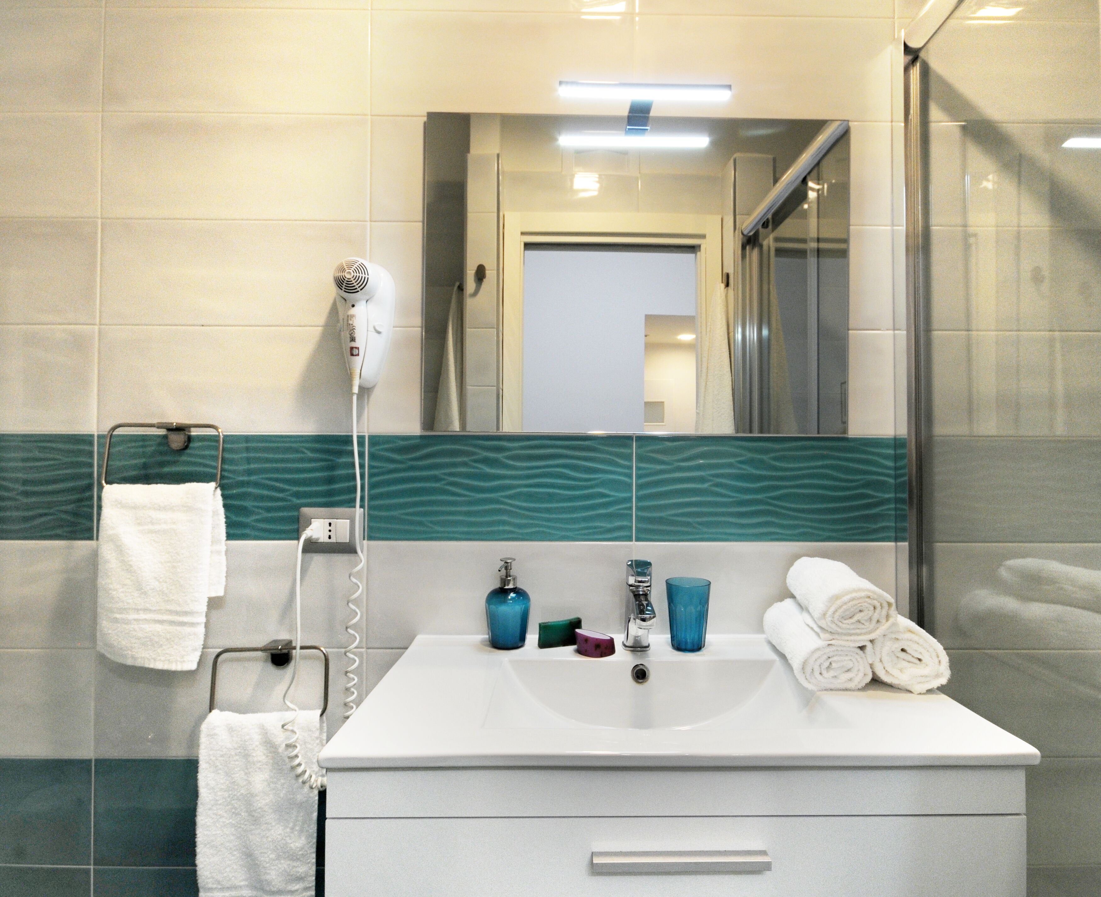 A bathroom with a white sink, a mirror, a hairdryer, and a towel rack.