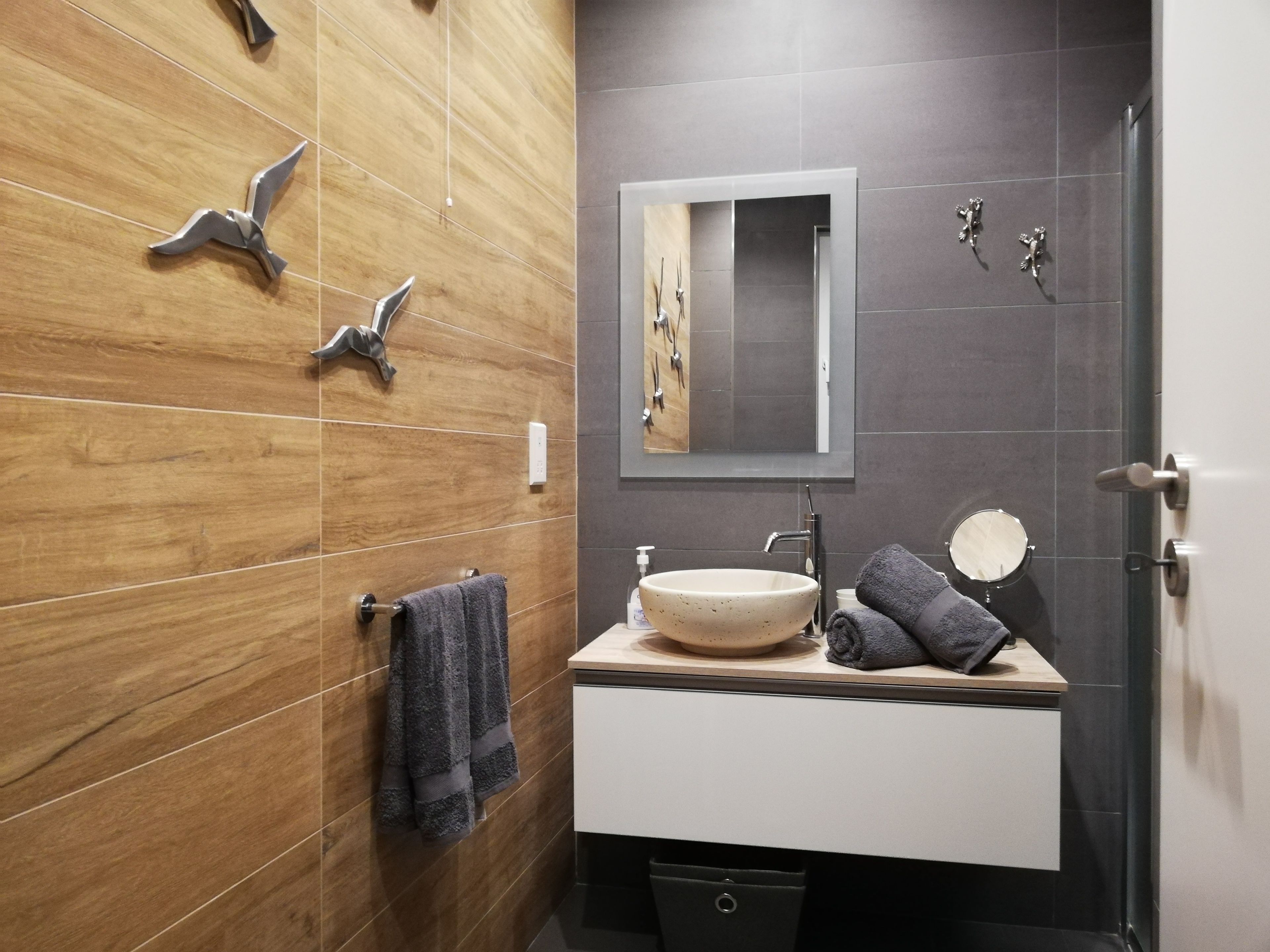 Une salle de bain moderne avec un meuble-lavabo en bois, un grand miroir et un lavabo sur pied.