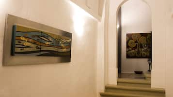 A hallway with a staircase leading to a landing. There are two artworks on the walls, one on the left and one on the right.